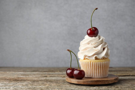 Delicious cupcake with cream and cherries on wooden table, space for textの写真素材