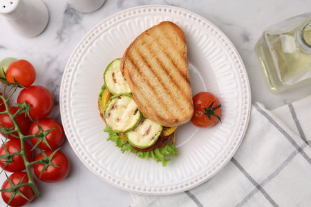 Tasty sandwich with grilled vegetables, fresh tomato and oil on white marble table, flat layの写真素材