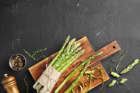 Fresh green asparagus stems and spices on gray textured table, flat lay. Space for textの写真素材