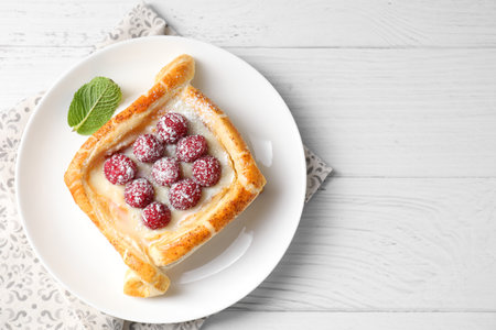 Tasty puff pastry with raspberries on white wooden table, top view. Space for textの写真素材