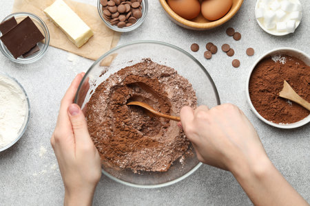 Woman making chocolate dough at light table, top view
