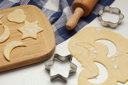 Raw dough, cookie cutters and rolling pin on white table, closeupの写真素材