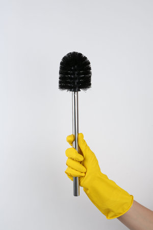Woman holding black toilet brush on light background, closeup. Cleaning toolの写真素材