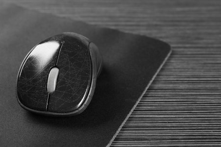 Computer mouse with mousepad on black wooden table, closeup. Space for text