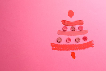 Christmas tree drawn with lipsticks on pink background, top view. Space for textの写真素材