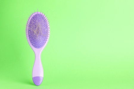 One brush with lost hair on green background, closeup. Space for textの写真素材