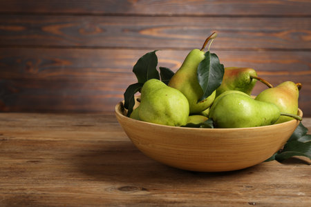 Fresh green pears and leaves in bowl on wooden table. Space for textの写真素材