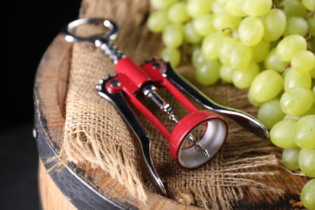 Wing corkscrew and grapes on wooden barrel, closeupの写真素材