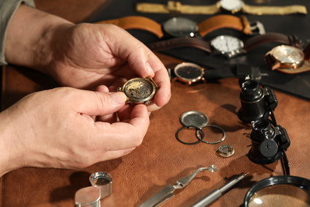 Man with mechanism of vintage wrist watch at table, closeup