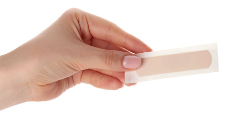 Woman holding medical adhesive bandage on white background, closeup