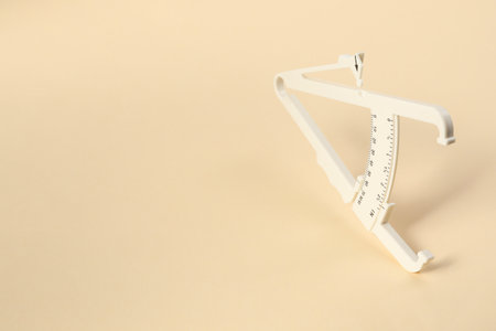 Plastic body fat caliper on beige background. Space for textの写真素材