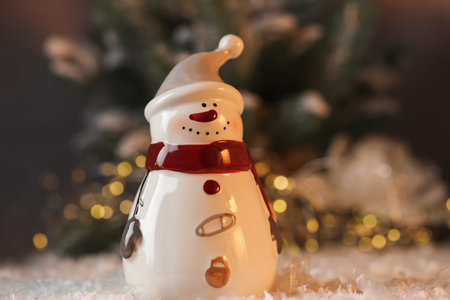 Funny snowman figure on artificial snow against blurred lights, closeupの写真素材