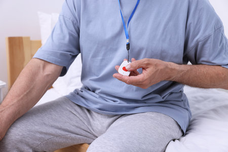 Senior man pressing emergency call button on bed in hospital, closeupの写真素材