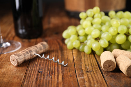 Corkscrew, corks and grapes on wooden table, closeupの写真素材