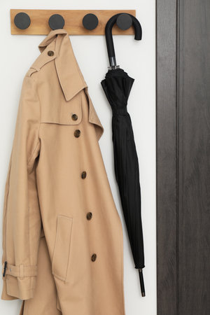 Black umbrella and coat on rack in hallway