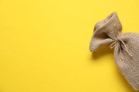 One burlap sack on yellow background, top view. Space for textの写真素材