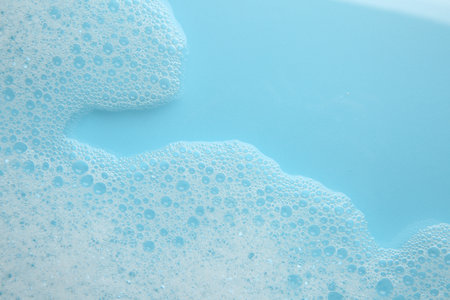 Washing laundry. White foam with bubbles on light blue background, top view. Space for textの写真素材