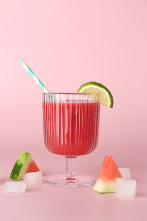 Tasty watermelon drink in glass, fresh fruits and ice cubes on pink backgroundの写真素材