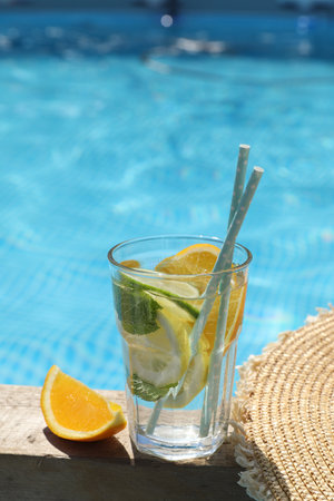 Tasty cocktail in glass near swimming pool outdoors