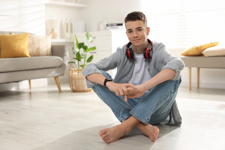 Full length portrait of teenage boy sitting on floor at home. Space for textの写真素材