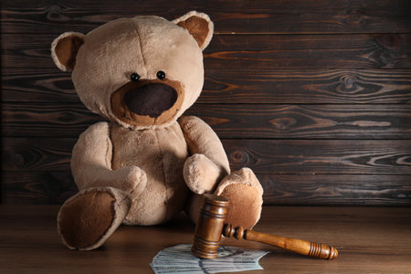 Alimony. Toy bear, gavel and dollar banknotes on wooden tableの写真素材