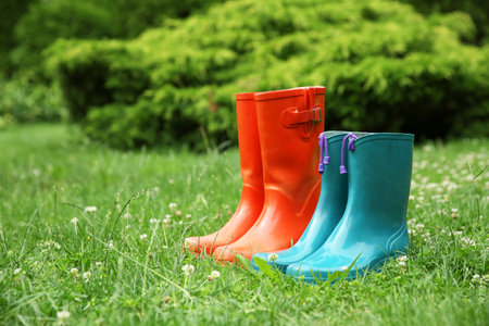 Two pairs of rubber boots on green grass outdoors