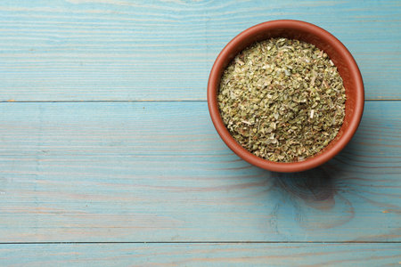Dried oregano in bowl on light blue wooden table, top view. Space for textの写真素材