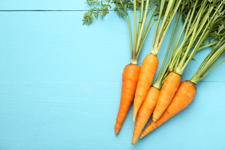 Tasty ripe juicy carrots on light blue wooden table, flat lay. Space for textの写真素材