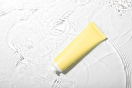 Cosmetic product. Tube with cream in water on light background, top viewの写真素材
