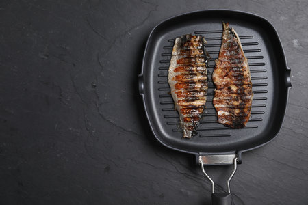 Delicious grilled mackerel in pan on dark textured table, top view. Space for textの写真素材