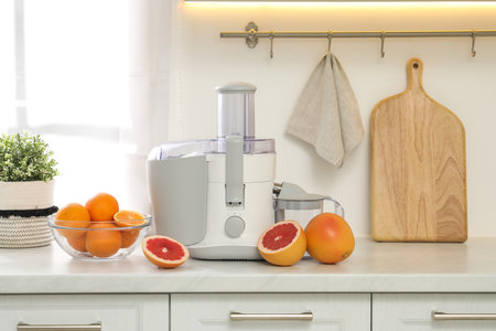 Modern juicer and grapefruits on white counter in kitchenの写真素材