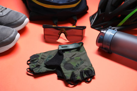 Bicycle helmet, backpack, sneakers, fingerless gloves, thermo bottle and goggles on coral...