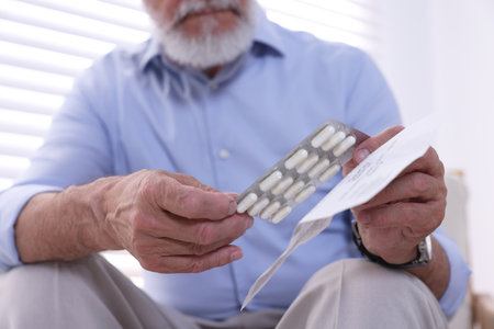 Senior man with pills and medicine instruction at home, closeupの写真素材