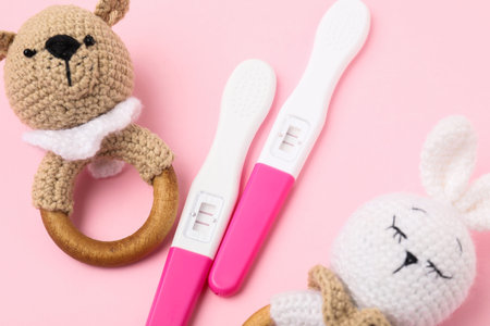 Pregnancy tests and baby rattles on pink background, closeupの写真素材