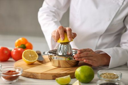 Woman squeezing juice out of lemon at table in kitchen, closeupの写真素材