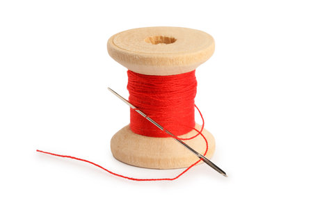 Spool of red sewing thread with needle isolated on white