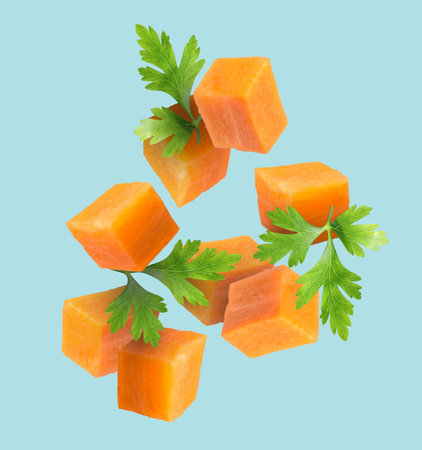 Carrot cubes and parsley in air on light blue backgroundの写真素材