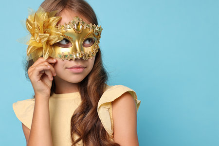 Cute girl wearing carnival mask on light blue background, space for textの写真素材