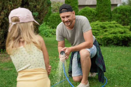 People watering lawn with hose in backyard, selective focusの写真素材