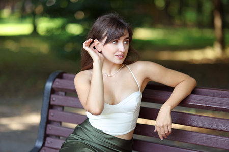Beautiful woman sitting on bench in parkの写真素材