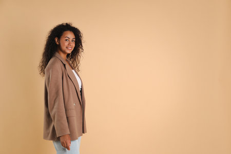 Beautiful woman in stylish jacket on beige background, space for textの写真素材