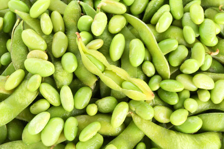 Raw green edamame pods on soybeans as background, closeupの写真素材