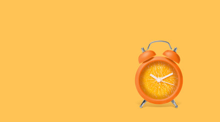 Juicy orange on alarm clock dial against light orange background. Creative poster with space for...