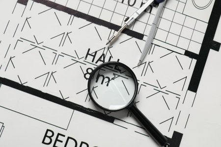 Dividers and magnifying glass on different architectural drawings, top view