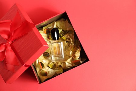 Open gift box with perfume bottle on red background, top view. Space for textの写真素材