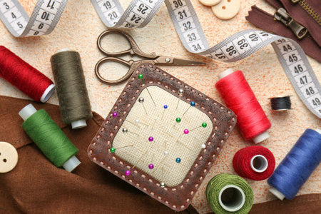 Flat lay composition with different sewing supplies on beige textured tableの写真素材