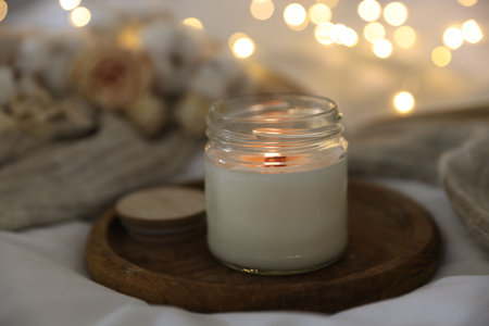 Burning candle on white cloth, closeup. Cozy atmosphere