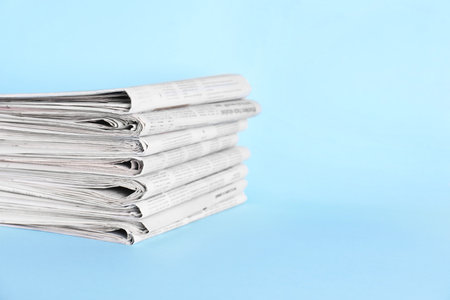 Stack of newspapers on light blue background, space for textの写真素材