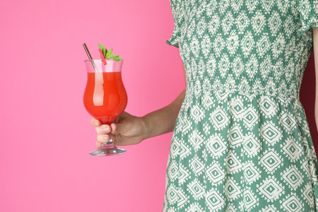 Woman with glass of refreshing cocktail on pink background, closeupの写真素材