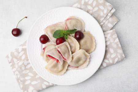 Traditional Ukrainian dumplings (varenyky) with cherries served on light table, flat layの写真素材